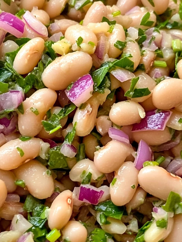 A white bean salad with onions and green leaves.