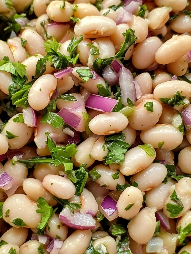 A white bean salad with onions and green herbs.