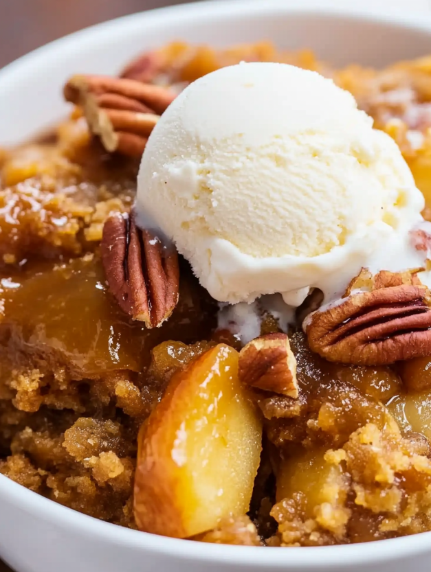 A scoop of ice cream on top of a crockpot apple dump cake.