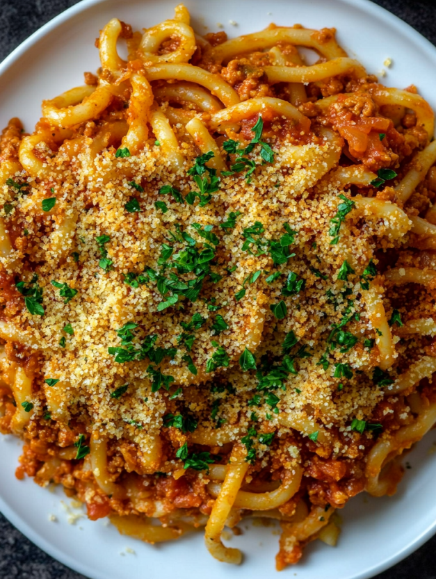 A plate of pasta with cheese and herbs on top.
