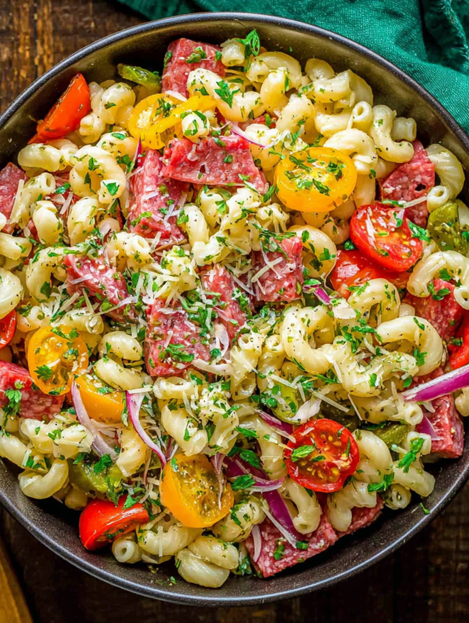 A bowl of Italian pasta salad with tomatoes, onions, and meat.
