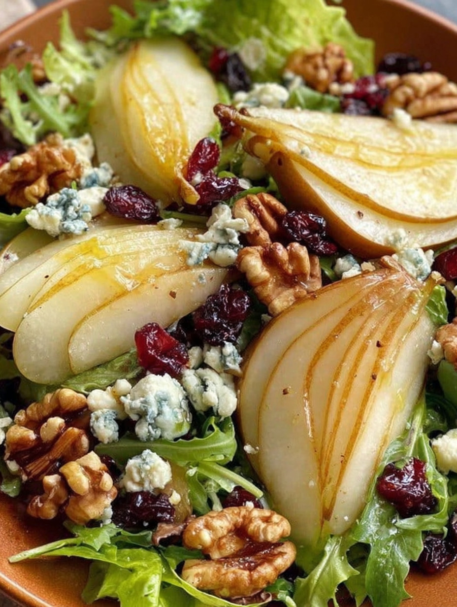 A salad with a slice of pear and blue cheese.