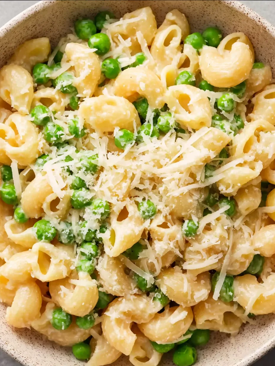 A bowl of creamy cavatappi pasta with peas and cheese.