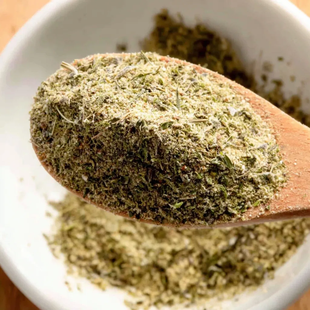 A wooden spoon in a bowl of homemade poultry seasoning.