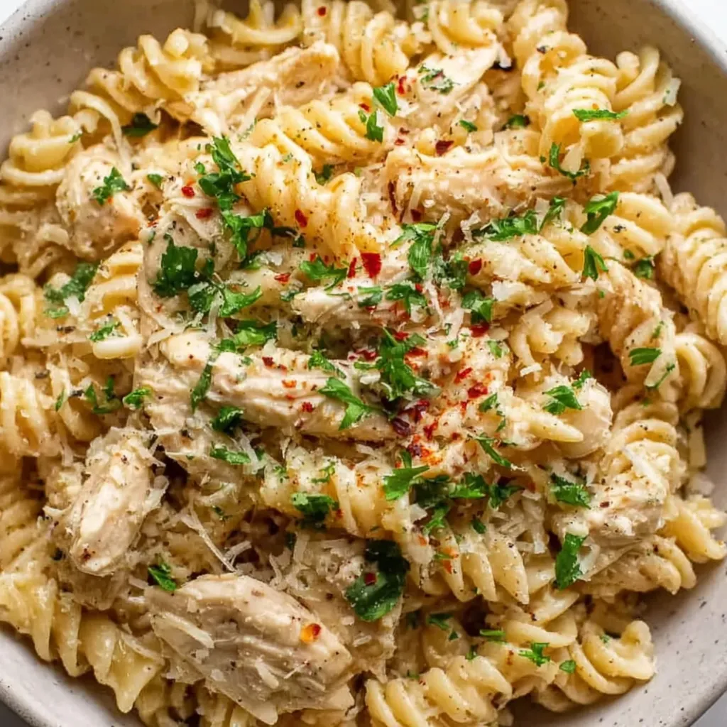 A bowl of pasta with chicken and Parmesan cheese.
