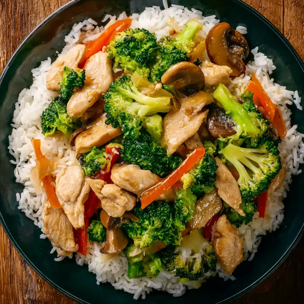 A plate of chicken stir-fry with broccoli and mushrooms.