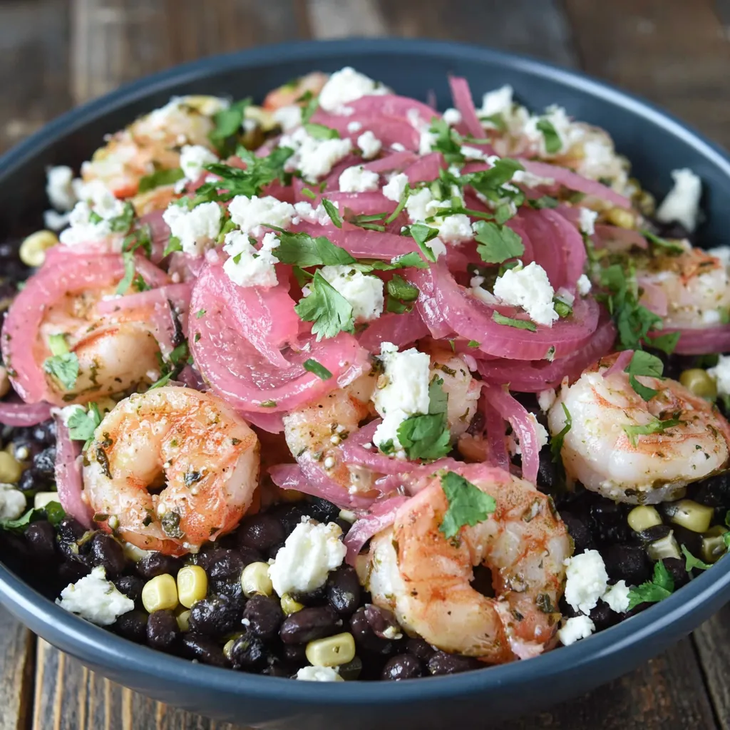 A bowl of black bean shrimp salad with corn and pickled onions.