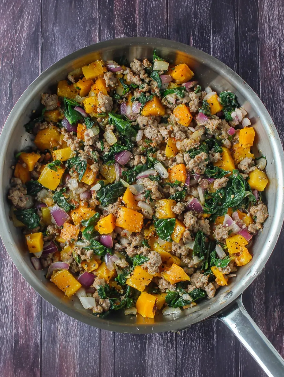 A pan of food with sausage, onions, and squash.