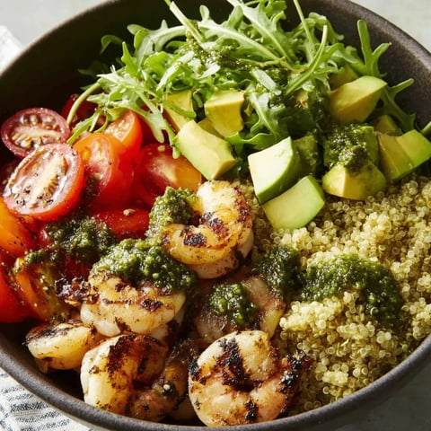 A bowl of food with shrimp, pesto, and quinoa.