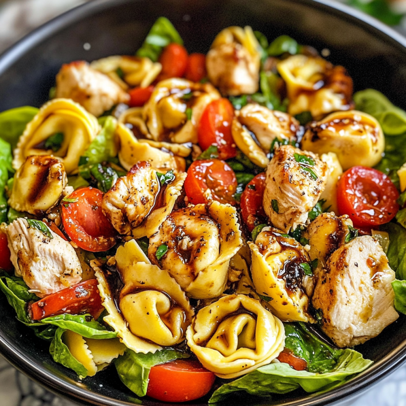 A bowl of warm tortellini tossed with chicken and fresh vegetables.
