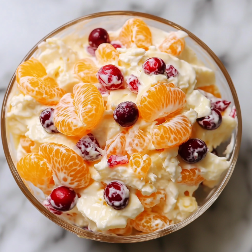 A bowl of fruit salad with oranges, cherries, and cranberries.