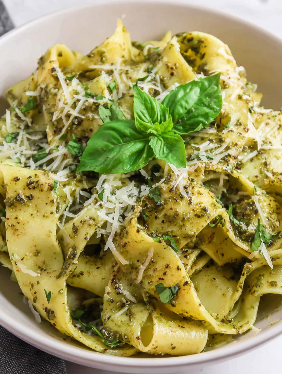 A bowl of pasta with pesto sauce.