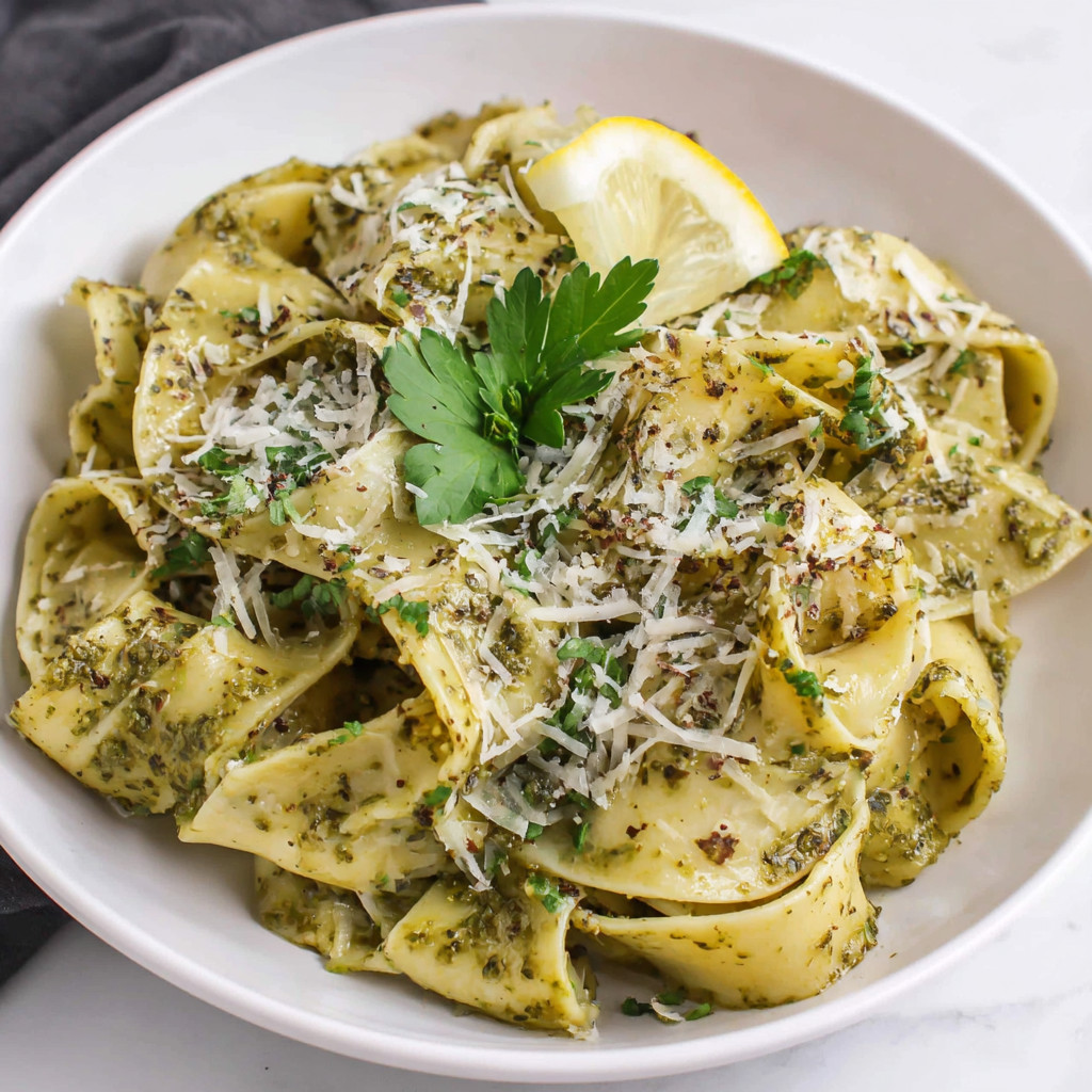 A bowl of pasta with pesto butter sauce.