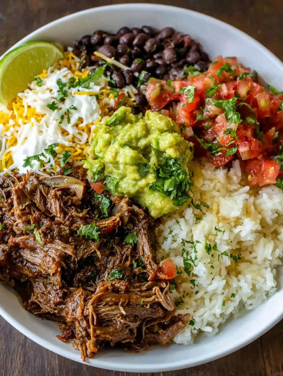A bowl of food with rice, beans, tomatoes, lime, and shredded beef.