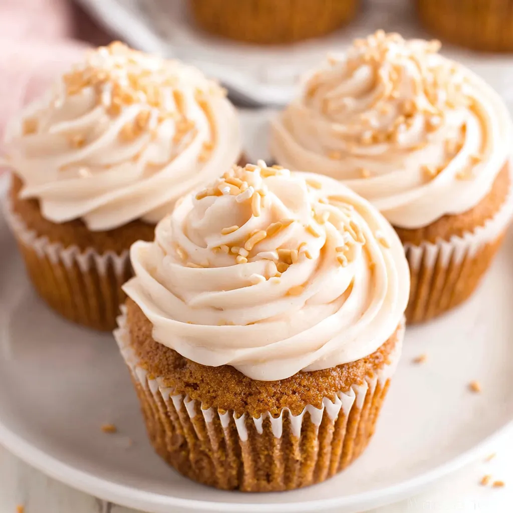 Three moist pumpkin cupcakes on a plate.