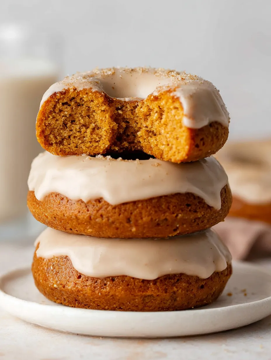 Three baked pumpkin donuts with icing.