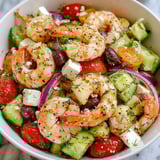 A bowl of shrimp, tomatoes, cucumbers, and feta cheese.